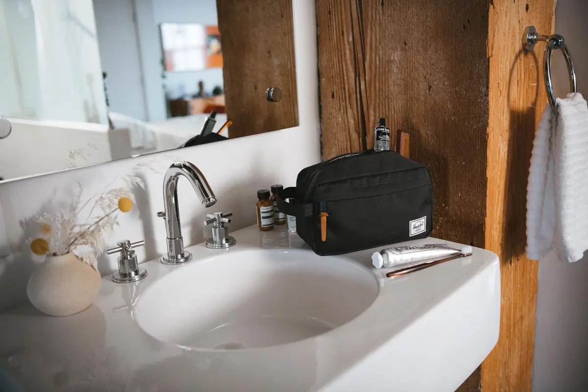 A Herschel Chapter Travel Kit Carry On Kit in black on the side of a bathroom sink.